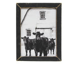 This wooden print features a white barn with three black cows, all in a charcoal drawing style. This print looks great with country decor and is held within a distressed black wooden frame. Display this sign hanging on a wall, using the keyhole hanger on the back of the frame, or lean it up on a tabletop or other flat surface.