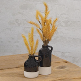 Add modern style to a coffee table with these vases. The jugs have narrow openings, small handles at the top, and are finished with a shiny black glaze with a beige, textured dipped stripe at the bottom. These jugs display beautifully alone or grouped together, empty or filled with floral and greenery stems, year-round or seasonally.   Your purchase includes one of each size vase.