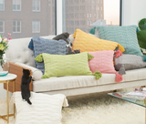 Bright green lumbar pillow with tassels   This handwoven pillow features a bright solid color that acts as a base layer, letting you mix and match with your favorite patterns and textures to build a one-of-a-kind pillow story. It is made with a cotton blend fabric dyed in a bright citron green color. Each corner is accented with a matching tassel.  This item is proudly made in the USA.  Materials: Cotton blend, polyester fill  Dimensions: 14" high x 4" deep x 22" wide