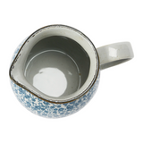 This beautiful pitcher features a hand-painted blue and white floral design accented by a light brown base. It is made of food-safe stoneware and a great size for creamer or salad dressing.   Materials: Stoneware  Dimensions: 4 3/4" wide x 6 1/4" high