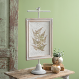 Green fern leaves pressed on white paper in distressed frame that is on pedestal, JaBella Designs