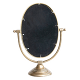 Aluminum framed mirror on stand with antique brass finish has black backing behind mirror