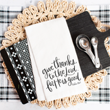 Decorative kitchen towel with text, measuring spoons, and books on a woven mat.