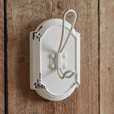White wall-mounted light switch with decorative design on a wooden panel