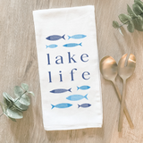 Blue 'Lake Life' kitchen towel  Form and function come together in this fun, flour-sack tea towel. Featuring a hand-drawn design, each towel has the phrase, "Lake Life," in dark blue letters. The phrase is surrounded by fish in light blue and dark blue shades. This would be a perfect gift for a lake enthusiast.   This item is proudly made in the USA.  Materials: Cotton  Dimensions: 27" wide x 27" long  Care: This item is machine washable.