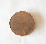 Brown leather coaster on a white surface