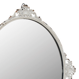 This small antique-inspired pieces features an oval glass mirror accented with a lightly distressed white metal frame with rust detail. This decorative metal mirror comes with 4 small feet for tabletop use and an attached metal hanger for hanging wall display. <br>