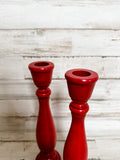 Add country charm to your dining room table with this candle holder set that complements almost any style, including rustic farmhouse and classic country. These two wood candlesticks are painted in a rich red finish and accented by a hand-rubbed black antiquing glaze. Both are finished with a clear matte wax sealer for durability. These candlesticks, which are made of a heavier wood than what is usually available at your local craft stores, each hold a standard size taper candle. <br>