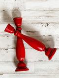 Add country charm to your dining room table with this candle holder set that complements almost any style, including rustic farmhouse and classic country. These two wood candlesticks are painted in a rich red finish and accented by a hand-rubbed black antiquing glaze. Both are finished with a clear matte wax sealer for durability. These candlesticks, which are made of a heavier wood than what is usually available at your local craft stores, each hold a standard size taper candle. <br>