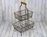 Double-tiered basket stand
Whether used to hold wrapped food or to display fresh fruit, this wired two-tier basket stand adds just the right amount of primitive style to your country kitchen. It features a rustic, distressed finished and a medium-toned brown wooden handle along the top.
Materials:
Metal, wood
Dimensions:
10” wide x 7” deep x 16” tall