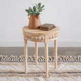 Small wooden side table with a woven basket and books on a rug