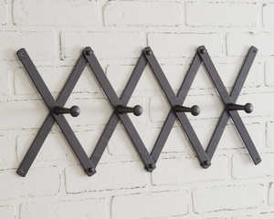Classic black accordion wall hanging coat rack

Simple and adjustable, this black accordion coat rack has four hooks for hanging coats, scarves, and bags. To hang this up, it has a small hole on the top and bottom of each edge for a nail or screw.

Materials:
Wood, metal

Dimensions:
3" high x 37" wide&nbsp;