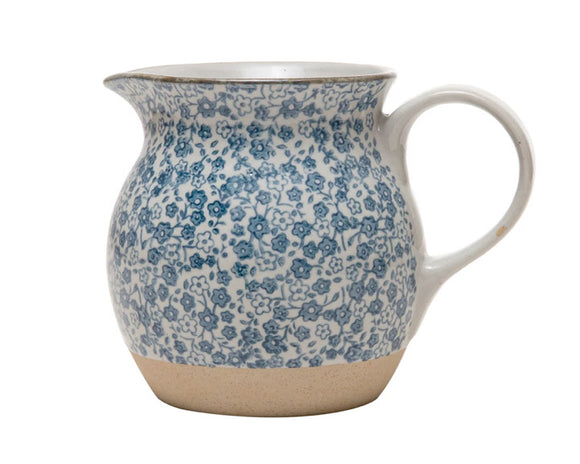 This beautiful pitcher features a hand-painted blue and white floral design accented by a light brown base. It is made of food-safe stoneware and a great size for creamer or salad dressing.   Materials: Stoneware  Dimensions: 4 3/4