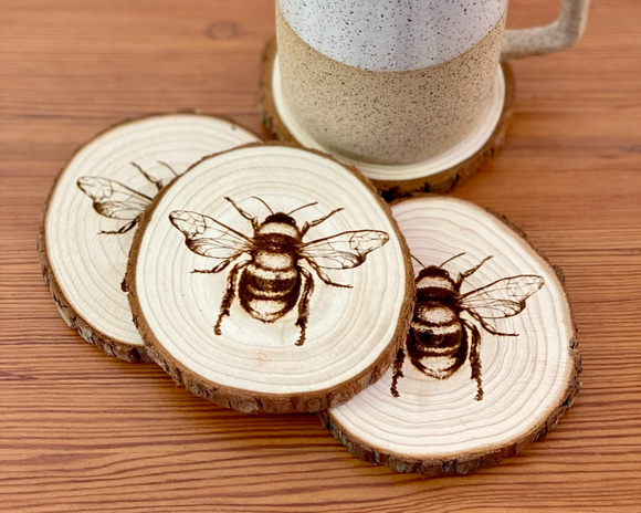 Engraved natural wood bumblebee coaster set
*Made to order*

Add cottagecore charm to a living room or bedroom with these coasters. They’re made from live edge California pine wood slices that are laser engraved with a honeybee illustration on one side. They are unfinished and smell quite nice. 

Materials:
Wood

Dimensions:
3/4
