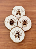 Engraved natural wood bumblebee coaster set
*Made to order*

Add cottagecore charm to a living room or bedroom with these coasters. They’re made from live edge California pine wood slices that are laser engraved with a honeybee illustration on one side. They are unfinished and smell quite nice.&nbsp;

Materials:
Wood

Dimensions:
3/4" thick 4" diameter
