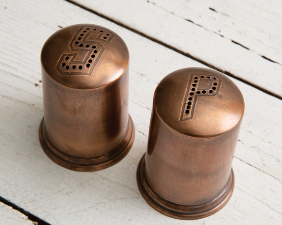 Display these vintage-inspired salt and pepper shakers on your dining room table for a classic look. The salt and pepper holes are hand stamped, and the center contains an insert and stopper for the salt and pepper.  Materials: Metal  Dimensions: 2