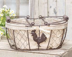 This decorative brown metal chicken-wire basket features a tall metal handle with a wooden grip. The basket features a brown metal rooster and is lined with taupe linen-style fabric, trimmed with a cream lace bow. Fill this basket with eggs, florals, or other decorative filler and display in the home year-round for a charming country touch.  Materials: Fabric, metal  Dimensions: 8" wide x 5" high x 12" long