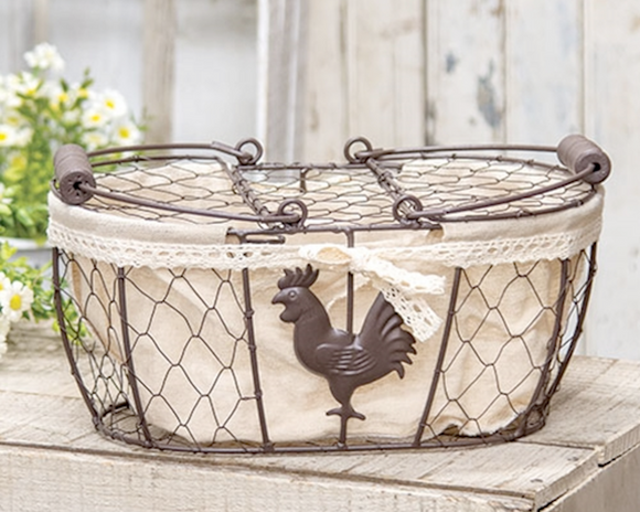 This decorative brown metal chicken-wire basket features a tall metal handle with a wooden grip. The basket features a brown metal rooster and is lined with taupe linen-style fabric, trimmed with a cream lace bow. Fill this basket with eggs, florals, or other decorative filler and display in the home year-round for a charming country touch.  Materials: Fabric, metal  Dimensions: 8