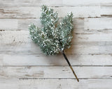Faux greenery branch with white berries on a wooden surface