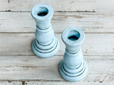 Two light blue candle holders on a wooden surface