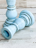 Decorative candle holder with a light blue finish on a wooden surface