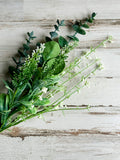 This decorative floral spray features a flexible green-wrapped stem. The spray is filled with lush branches of dark eucalyptus greenery alongside stems of white baby’s breath blooms. This spray is a beautifully addition to an artificial arrangement and would also work well in a wreath. Whether used in country cottage wedding centerpieces or holiday decorations, these sprays are perfect for your next event.  This spray is sold individually.  Materials: Artificial greenery  Dimensions: 19" long