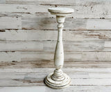 White distressed candle holder on a wooden surface