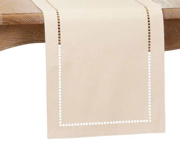 Beige table runner with white hemstitching on a wooden table