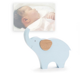 This decoupaged blue elephant-shaped photo holder features a wooden clip on the back of the trunk. The wooden elephant has a raised wood grain ear. It can be used for photos, notes, or just as a shelf sitter. This is a lovely choice for a baby shower gift.<br>