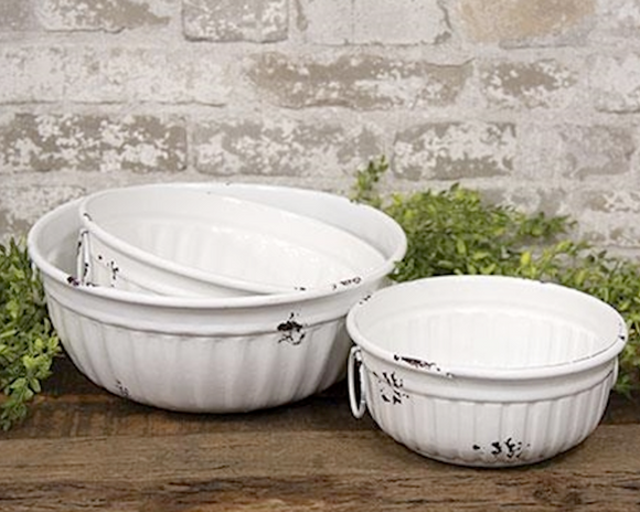 This set of three antiquated white nesting bowls feature simple impressions around the outside. Each bowl comes with two circular white handles attached on opposite ends. Use these bowls to display fruit or packaged baked goods in the kitchen or fill with greenery and florals. 
