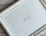 Decorative frame with ornate frame and 'jabeila designs' branding on a wooden surface.