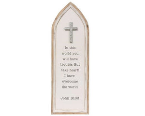 This wooden sign features a cathedral window design. It has a natural wood frame and cream background that reads, "In this world you will have trouble. But take heart! I have overcome the world -- John 16:33," in black lettering. It is accented by a cross at the top and comes ready to hang for immediate display. At almost 3 feet long this sign is perfect for a hallway or transition wall between a living room and kitchen.