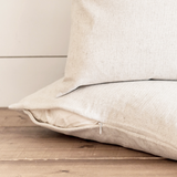 Beige fabric pillow on a wooden surface with a neutral background
