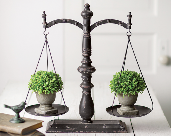 Decorative scale with two potted plants on a white background