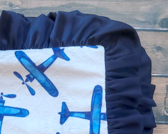Made from high-quality Minky fabrics, which comprise luxuriously soft microfibers, this navy blue airplane baby blanket features a complementary navy blue satin ruffle trim. It is the perfect size for nap time cuddles. This blanket would be a great choice for a baby shower gift.

This item is proudly made in the USA.