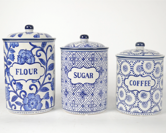 Set of three blue and white ceramic canisters labeled 'Flour', 'Sugar', and 'Coffee' on a white background.