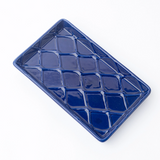 Blue ceramic tray with diamond pattern on a white background