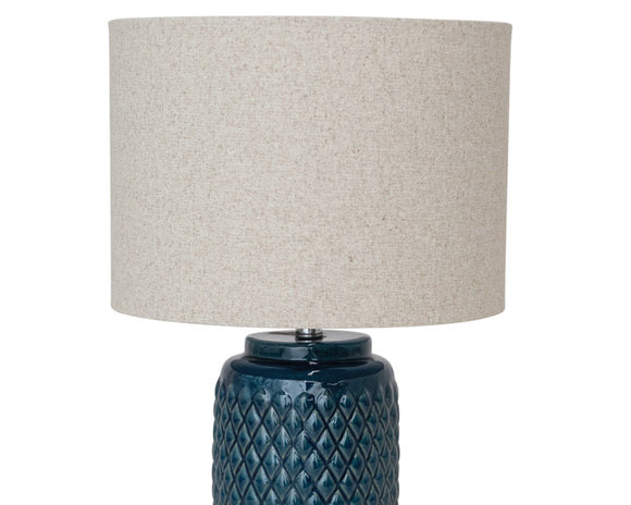 Embossed dark blue ceramic table lamp

Whether used in an entryway or on a bedside table, this lamp is perfect for adding a pop of color to your space. It is made of ceramic and features an embossed reactive glaze, which means each one will have its own unique characteristics. It comes with a neutral-toned linen shade to complete the look.

Materials:
Ceramic, metal, linen

Dimensions:
15