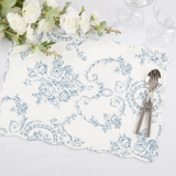 Decorative blue and white floral patterned placemat with cutlery and flowers on a table.