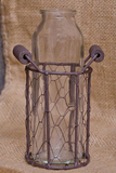 Add rustic charm to a kitchen table with this adorable vase. It features a glass bottle in a rustic wire basket with chicken wire mesh sides and two small handles. It's a great size for small flowers.

These vases are sold individually or in sets of three.

Materials:
Glass, metal

Dimensions:
4" diameter x 6 1/2" high