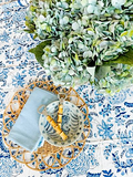 Tea set on a decorative tablecloth with green foliage