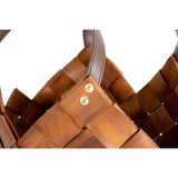 Close-up of a brown woven basket with brass rivets on a white background