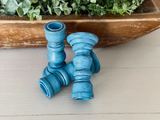 Blue decorative candle holders on a wooden surface with greenery in the background