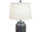 Bold yet refined, this handcrafted fibercast table lamp features a cylindrical base with subtle horizontal ridge detailing in a deep distressed charcoal finish. The textured surface adds depth and modern sophistication, while the neutral dark tone makes it a versatile statement piece for contemporary, rustic, or transitional interiors. Finished with a crisp white linen shade and a coordinating charcoal finial, it provides both style and substance to any room.

This item is proudly made in the USA.