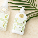 Hand soap and lotion set with green leaf design on a wooden surface