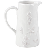 White ceramic pitcher with embossed sea-themed designs on a white background