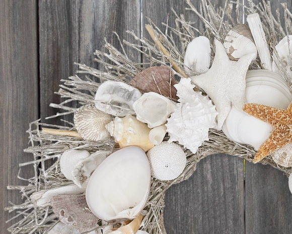 Decorative wreath with seashells and driftwood against a wooden background