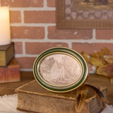 Decorative framed picture on an old book with a brick wall and candle in the background