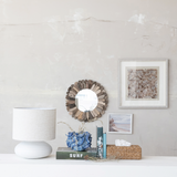 Decorative items including a lamp, mirror, and books on a shelf against a light gray wall.