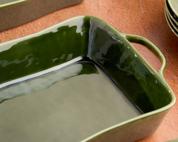 Green ceramic baking dish on a wooden surface